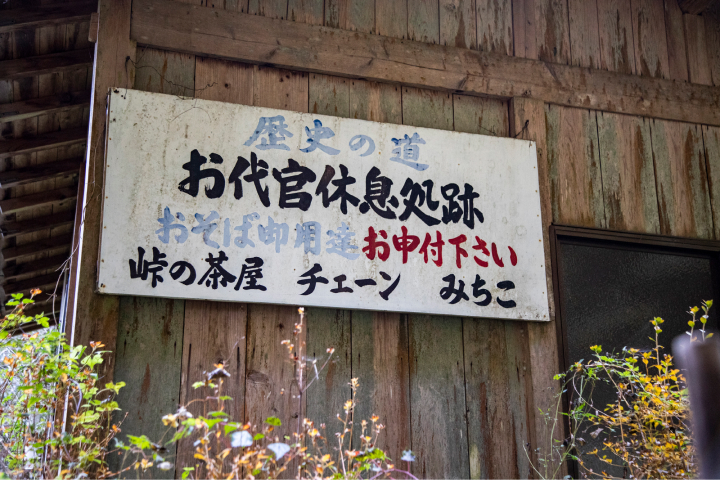 手書きの看板「歴史の道、お代官休息処跡、おそば御用達お申し付け下さい、峠の茶屋 チェーン みちこ」