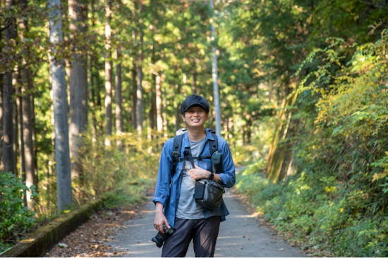 登山を終え、舗装された道に立つJINさん