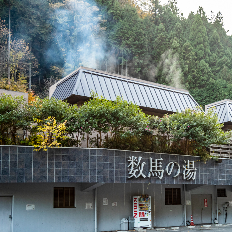 「数馬の湯」の看板。建物の奥から湯気が立ち上っている