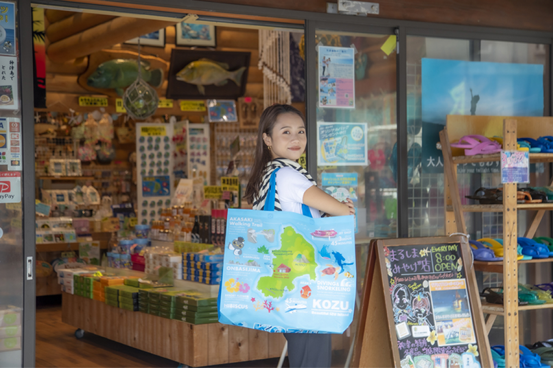 神津島のイラストが入った水色の神津島バックを肩にかけているアオイさん