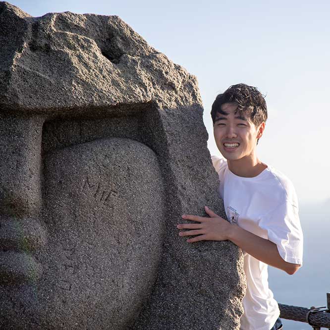 石像に手を添えて笑顔の石橋さん