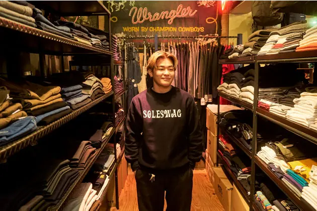 金髪に黒に白文字の「SOLESWAG」のロゴが入ったスウェットを着た男性スタッフの一枚