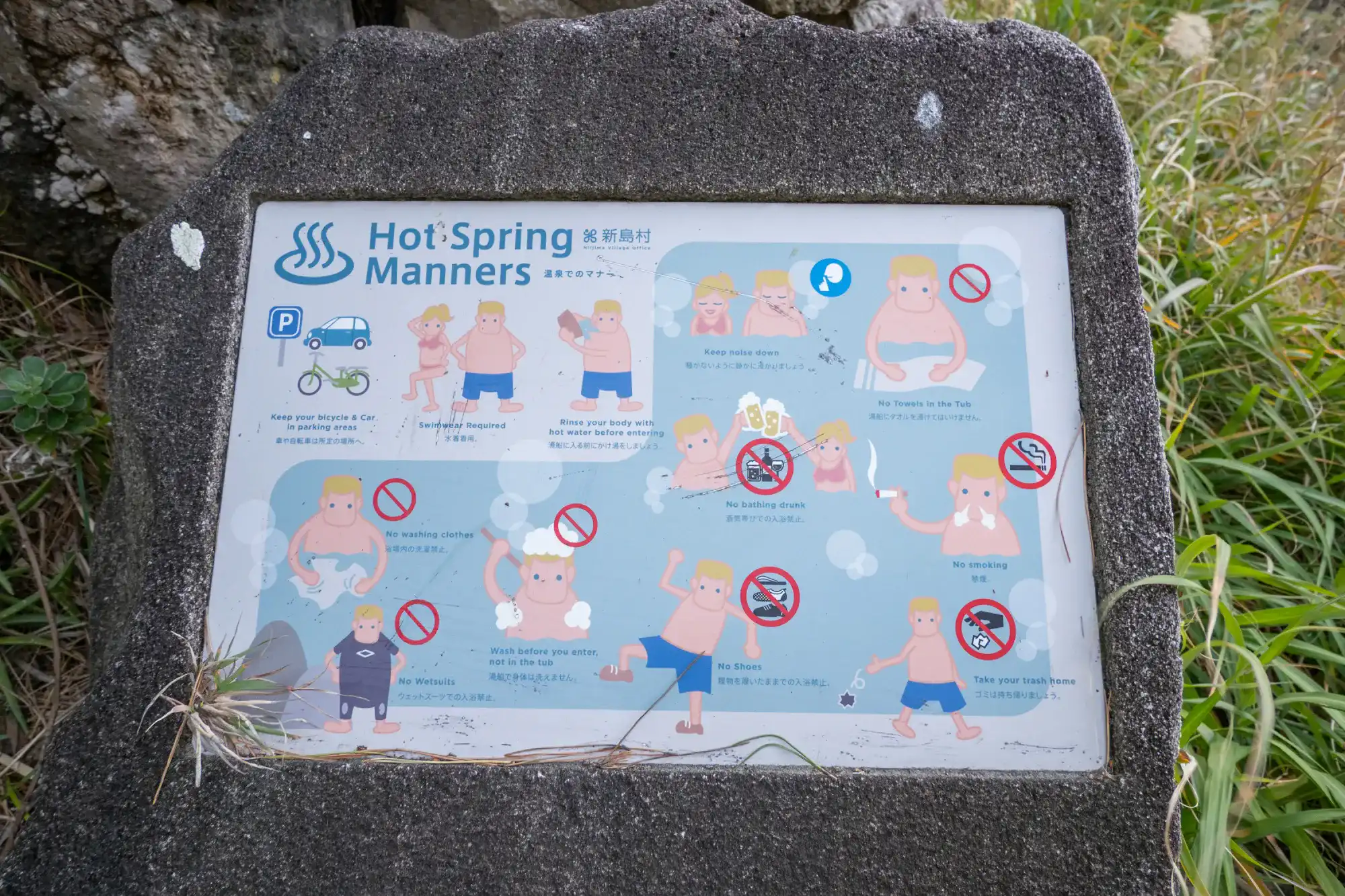 岩にはめ込まれた温泉の注意事項の看板