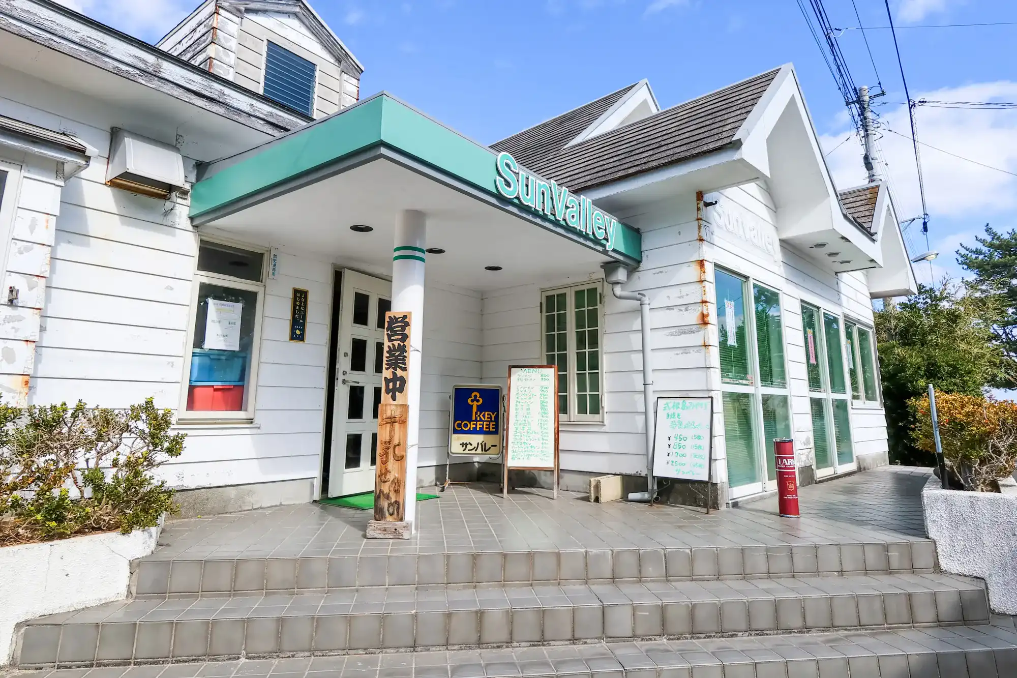白い壁に緑の看板のサンバレーの外観