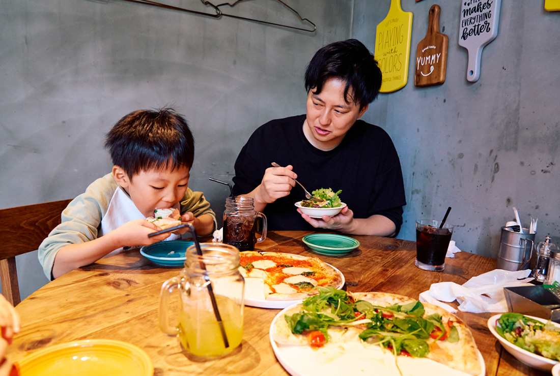 ピザを頬張るいおりくん、サラダを食べるパパ