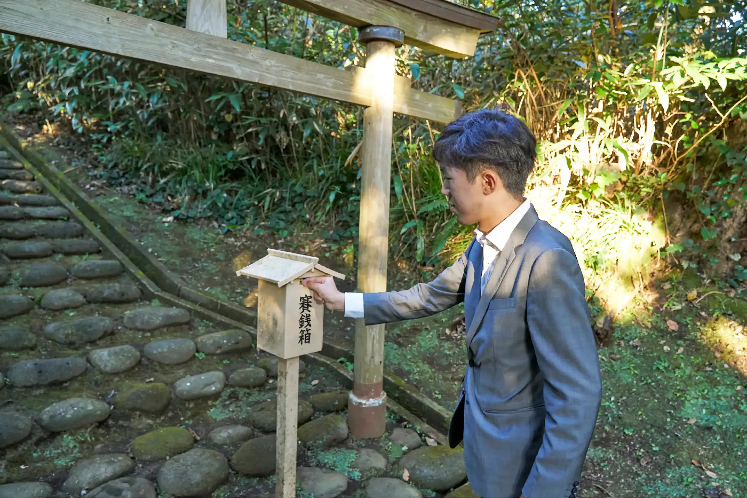 阿豆佐和気命神社本宮の賽銭箱にお賽銭を入れるスーツさん