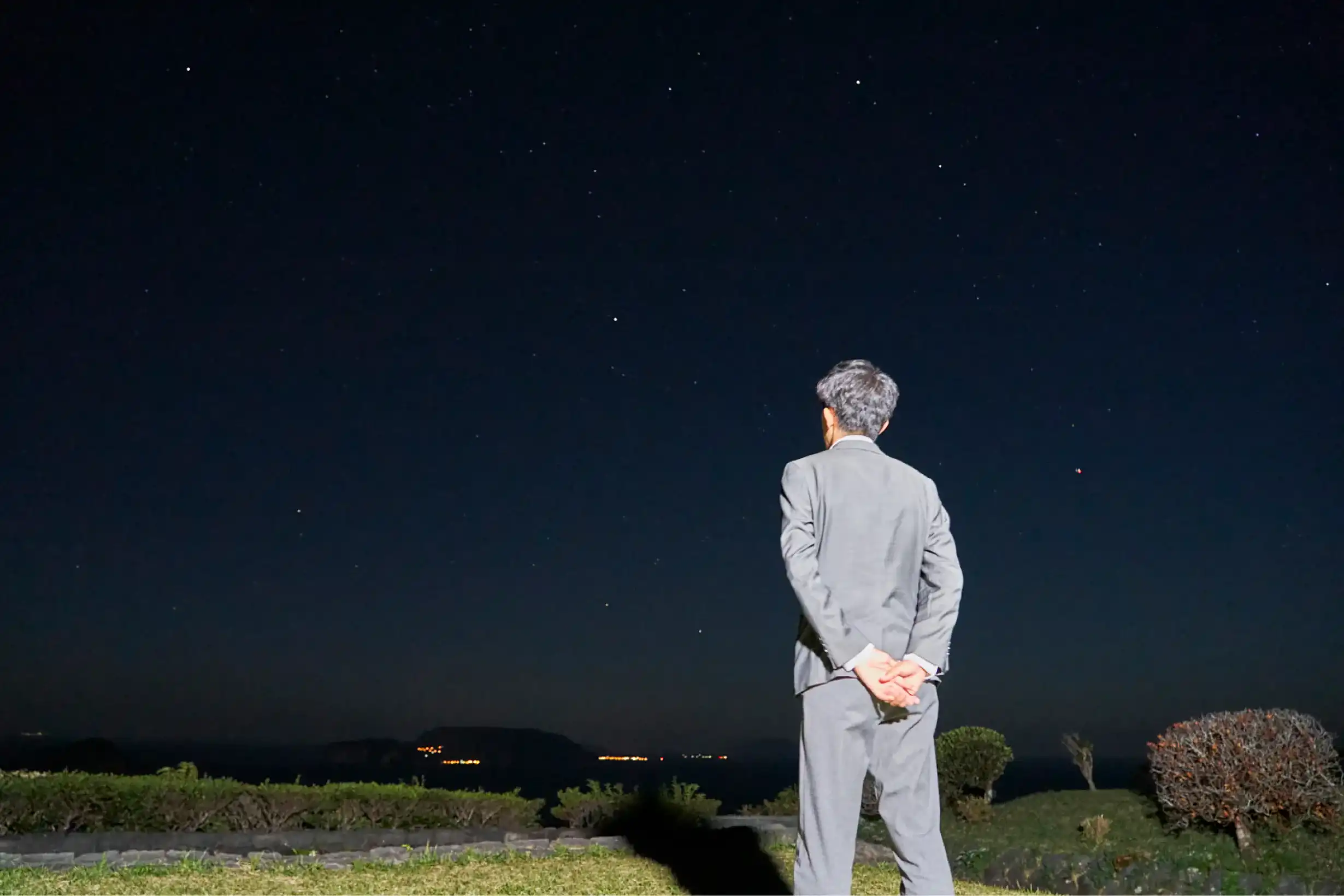 他の島の夜景を眺めるスーツさん
