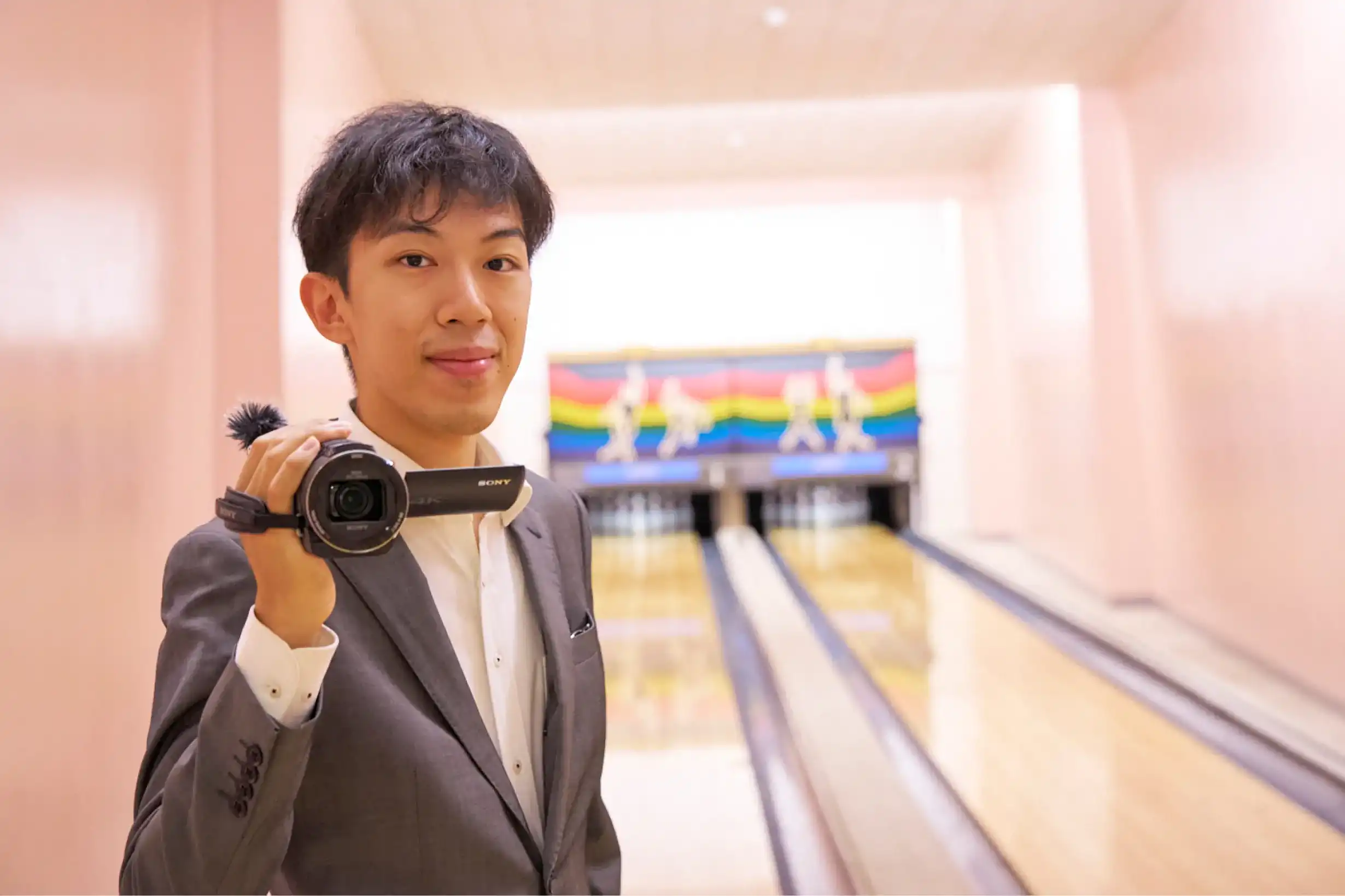 レーン前でカメラを構えるスーツさん