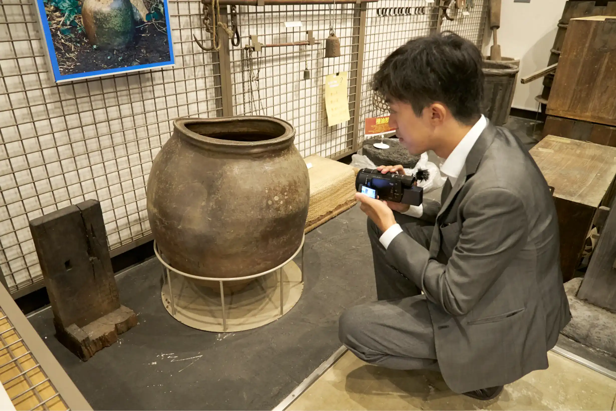 屈んで水瓶を調べるスーツさん